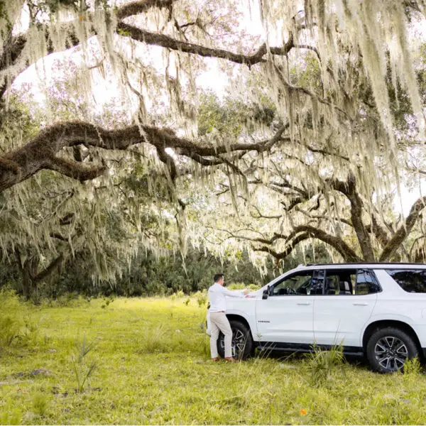 John Evans reviewing land plans by his truck underneath an Oak tree.